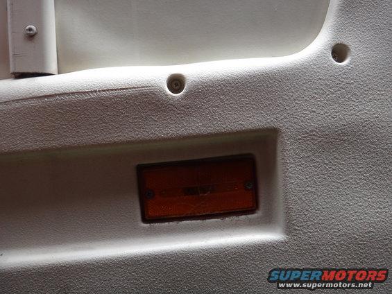 Interior panel with textured surface and an amber marker light. Text 'SUPERMOTORS.NET' visible