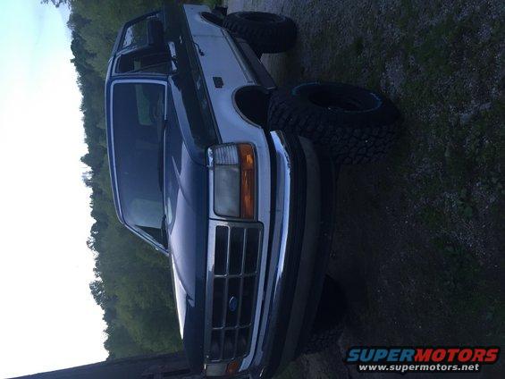 Dark blue Ford Bronco with chrome grille and aftermarket wheels, parked outdoors