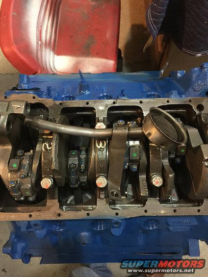 Engine block with crankshaft, connecting rods, and oil pickup tube visible. Blue painted block
