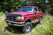 1995 Ford Bronco - Red 1995 Ford Bronco with aftermarket wheels and tires, parked outdoors.