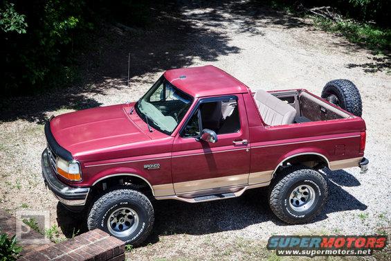 1995 Ford Bronco, red with tan trim, parked on a gravel driveway