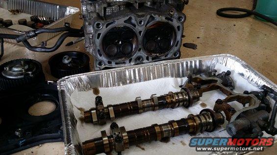 Engine cylinder head and camshafts in a metal tray with paper towels