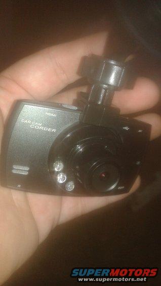 Hand holding a black car dash camcorder with 'CAR CAM CORDER' and 'HDMI' text visible