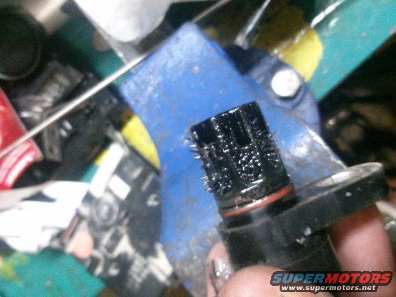 speed sensor covered in metal shavings, held in a vise