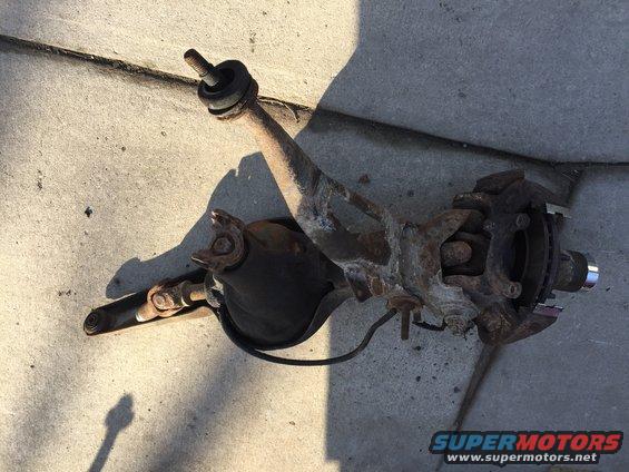 Rusty front suspension part with a U-joint and brake rotor
