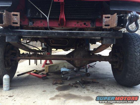 Front axle and suspension of a red 1996 Ford F-150, undergoing maintenance