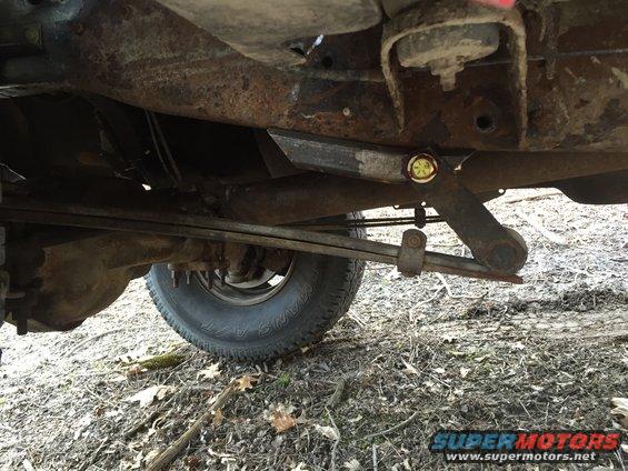 Underside view of a rusty pickup truck's rear suspension and leaf springs