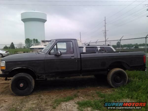 Side view of a dark gray pickup truck with a water tower in the background