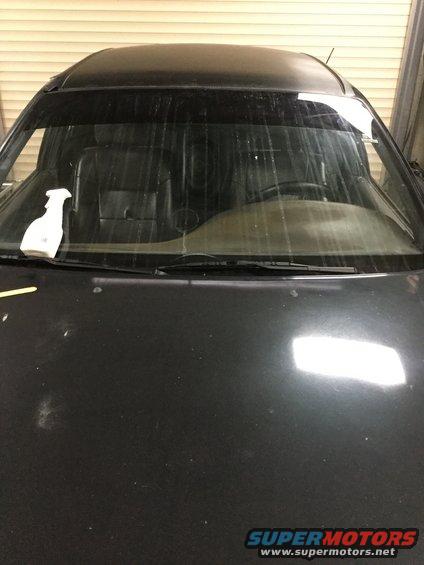 Car hood and windshield interior. Spray bottle on dashboard