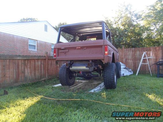 Rear view of a 1972 Ford Bronco in a backyard, showing its lifted suspension and off-road tires