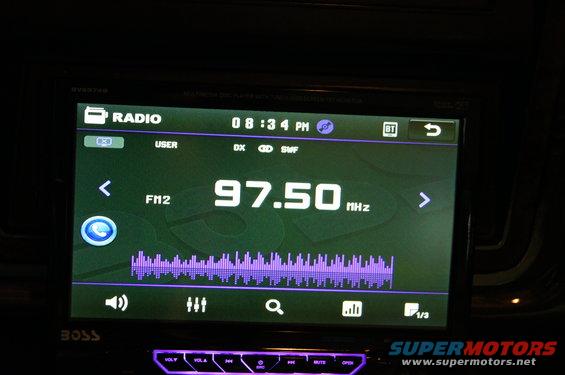 Car stereo display showing radio station 97.50 MHz and equalizer