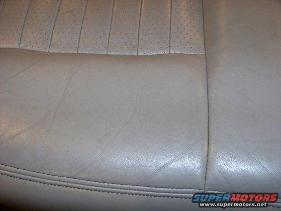 Close-up of light-colored perforated leather seat upholstery with visible stitching