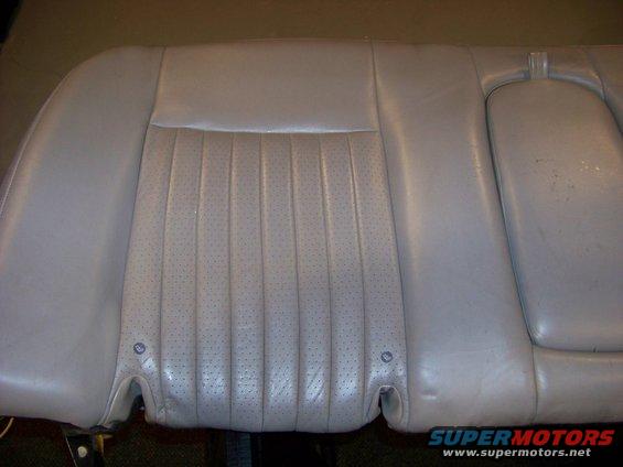 Light gray perforated leather car seat back with vertical pleats and a headrest