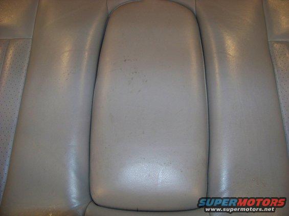 Tan leather rear seat armrest with visible wear marks