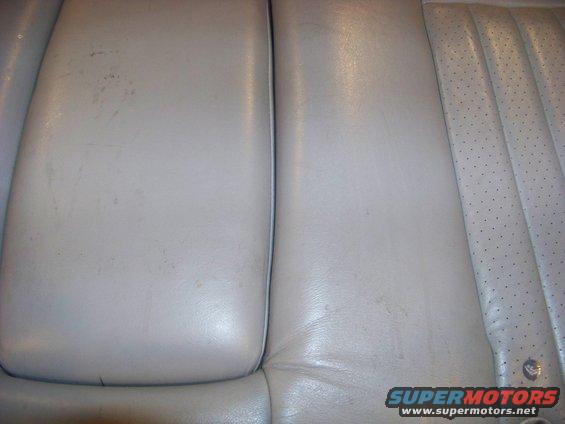 Close-up of light-colored leather car seats, showing stitching and perforated sections