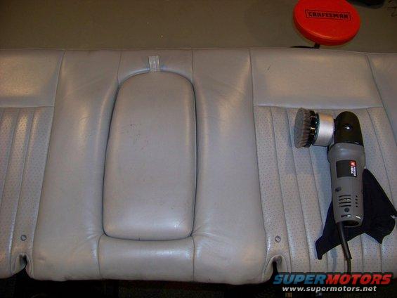 Light gray perforated leather rear car seat with a polishing tool and a red Craftsman buffer