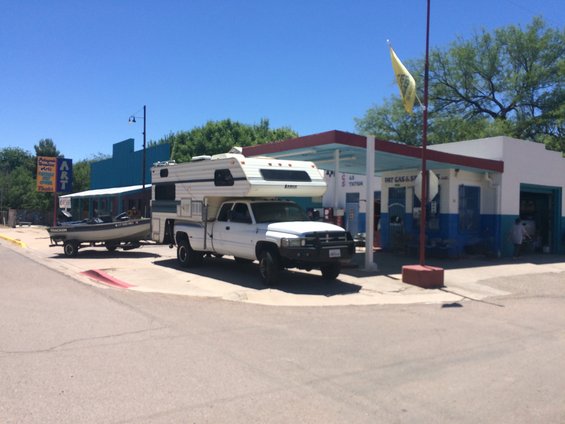 White pickup truck towing a boat trailer parked at a gas station
