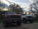 1996 Ford Bronco - Two Ford Broncos are parked side-by-side in a driveway under a cloudy sky.