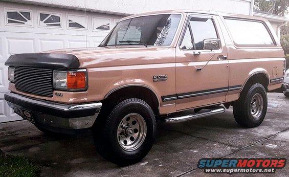 Tan 1987 Ford Bronco parked in front of a garage