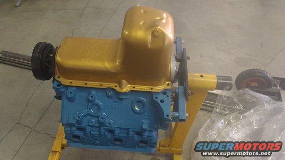 Blue engine block with gold oil pan on yellow stand