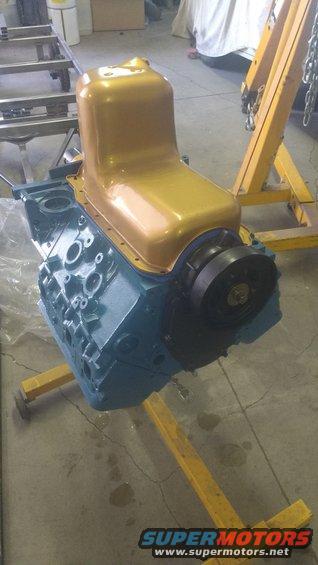 Blue engine block with gold oil pan on yellow stand