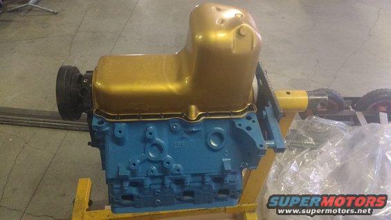 Blue engine block with a gold oil pan on a yellow stand