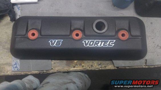 Black engine valve cover with V6 Vortec branding and orange grommets