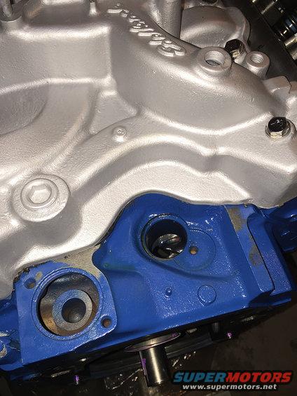 Close-up of a blue and silver engine block casting with bolt holes and openings