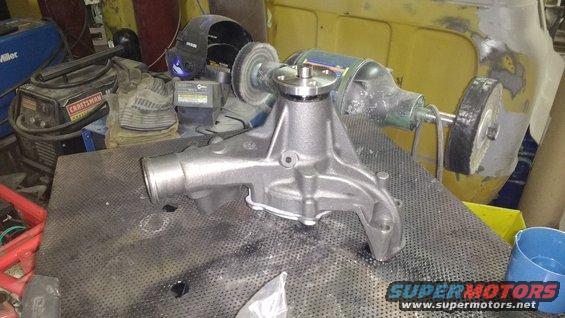 Car water pump on a workbench with a grinder and welding equipment in the background