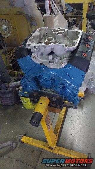 Blue engine block with aluminum intake manifold on a yellow engine stand