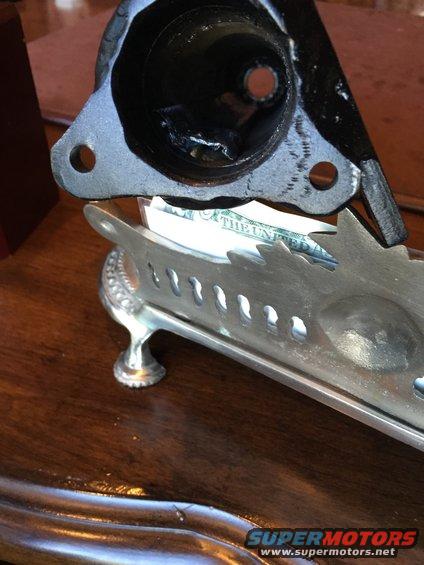 Metal automotive part resting on a silver tray holding US currency
