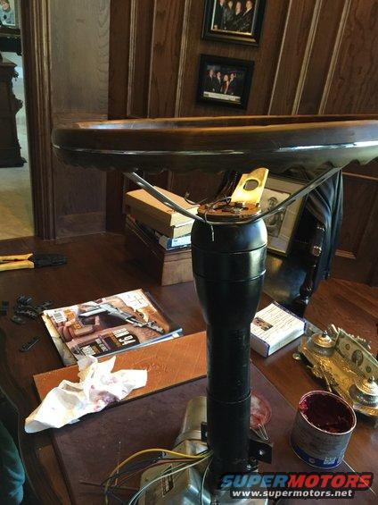 Steering column and wooden steering wheel on a table with tools and a magazine