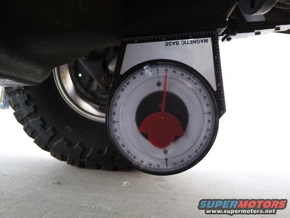 Magnetic base inclinometer tool attached to vehicle suspension near tire