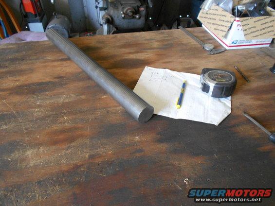 Metal shaft with fluting on a workbench next to a tape measure and notes