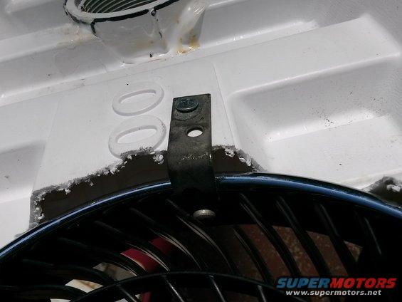 Air conditioner fan mounting bracket attached to white plastic housing