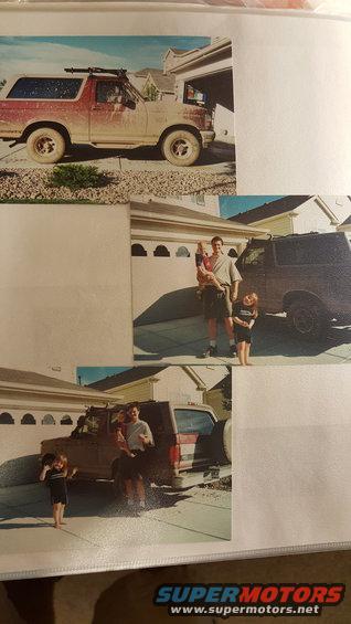 Red and tan Ford Bronco parked in a driveway, covered in dust, with a roof rack