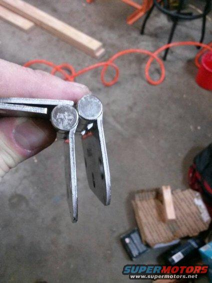 Close-up of two metal hinges being held by a hand