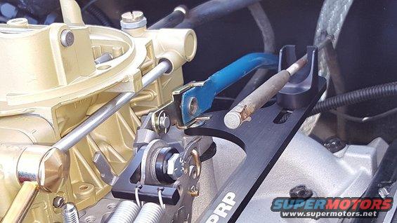 Gold carburetor with black and blue linkage assembly, showing a metal rod and springs