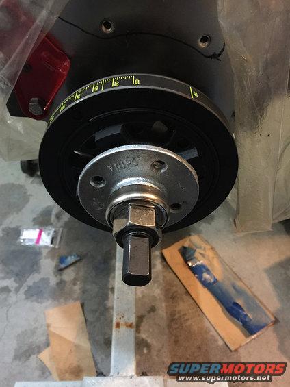 Close-up of engine crankshaft pulley with timing marks and a large bolt in the center