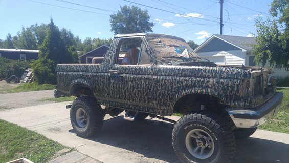 Camouflaged Ford Bronco with lifted suspension and off-road tires parked on a driveway