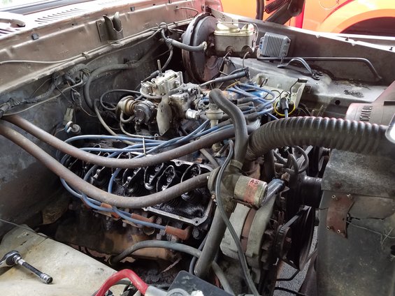 Engine bay with V8 engine, carburetor, distributor, and alternator visible
