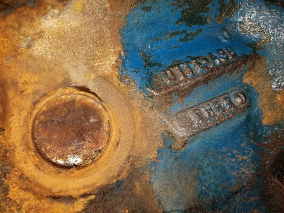 Cast iron engine part with blue and rust-colored paint, showing casting numbers D1TA-9A38 and 8H20