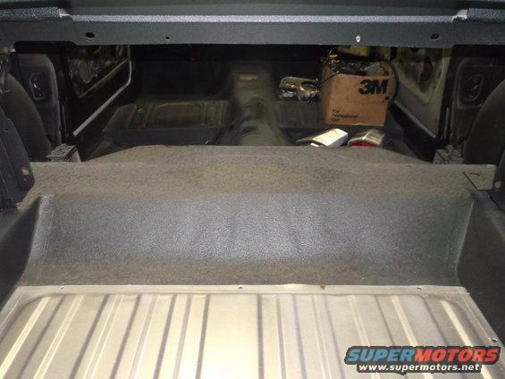 Interior of a car with carpeted floor and metal trunk area. A box with "3M" logo is visible