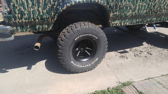 1991 Ford Bronco with camouflage paint, large off-road tires, and a visible exhaust pipe
