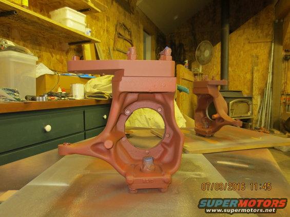 Two red-painted Dana 60 axle knuckles sit on a workbench in a garage