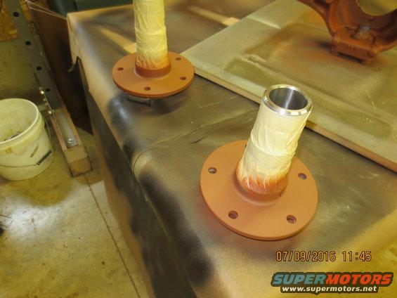 Two axle shafts with flanges, taped and painted orange, on a workbench