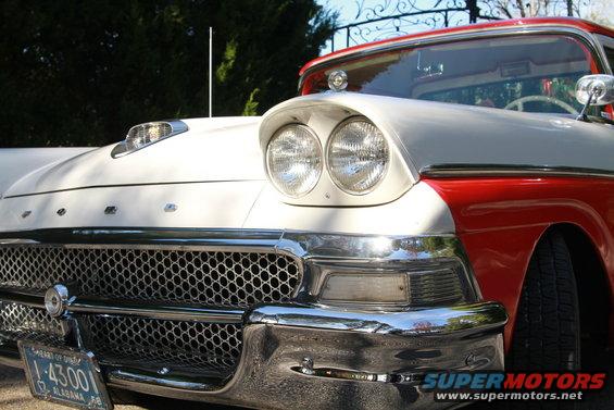 Front of a red and white 1957 Ford Fairlane 500 with a prominent grille and dual headlights