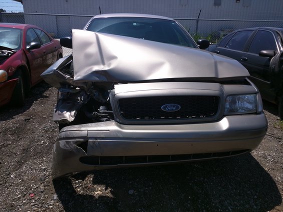 Gold 2007 Ford Crown Victoria with severe front-end damage, parked outdoors