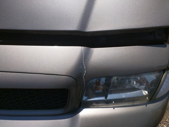 Grey car hood cracked near headlight