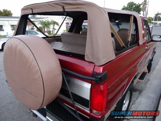 Red 1994 Ford Bronco convertible with tan soft top and spare tire